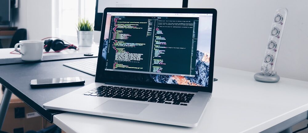 Екран MacBook з рядками коду на робочому столі